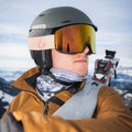 Un uomo in tenuta da sci e casco, che indossa gli occhiali da sci The SOLAR kompakte di NAKED Optics, tiene gli sci in spalla con le montagne innevate sullo sfondo.