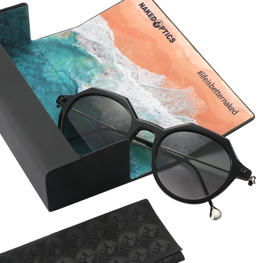 The IZZY by NAKED Optics is a black, round sunglasses model with an acetate frame and UV400 protection, and it comes with a cleaning cloth featuring a beach scene and the text “lifeisbetterwalked.”.