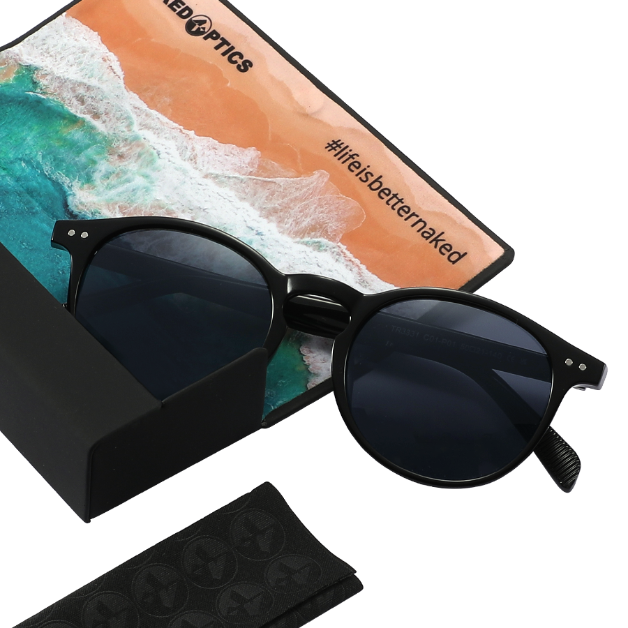 Black sunglasses with dark lenses—such as The WHOOP by NAKED Optics, featuring UV400 protection and polarized lens technology—rest beside a beach-themed card that says #lifesbetternaked.
