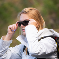Une personne vêtue d'une veste blanche en train d'ajuster ses lunettes de soleil noires The RAVE.
