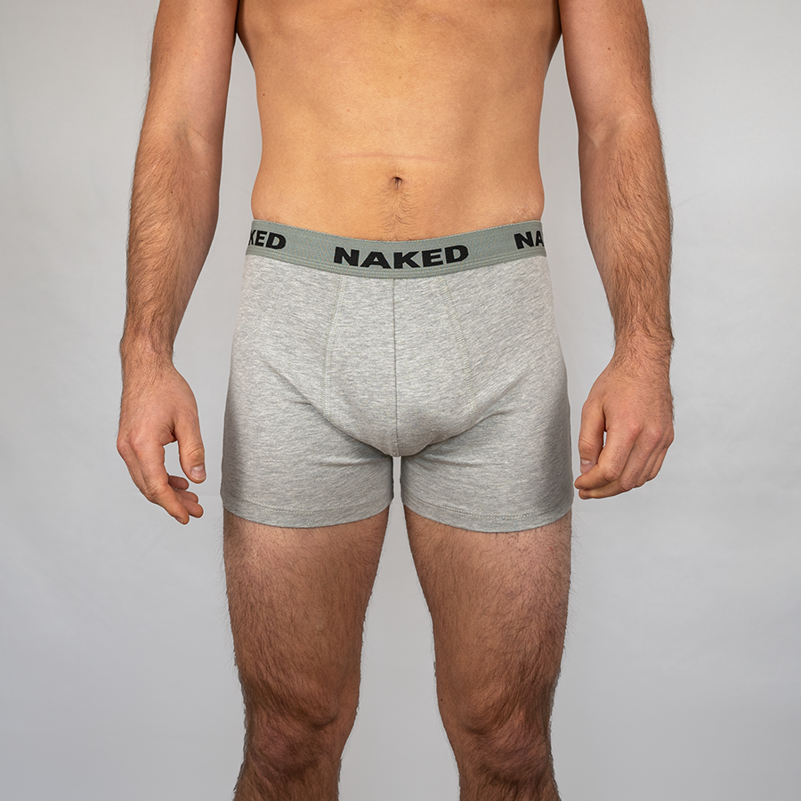 Un homme portant un boxer gris de la marque NAKED Optics, avec un logo sur la ceinture.