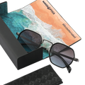 Occhiali da sole neri “The ICON” di NAKED Optics con montatura in metallo, presentati in una custodia con motivo marino e le scritte #lifeisbettermaked e NAKED OPTICS. Dotati di protezione UV400 per una protezione ottimale nelle giornate di sole.