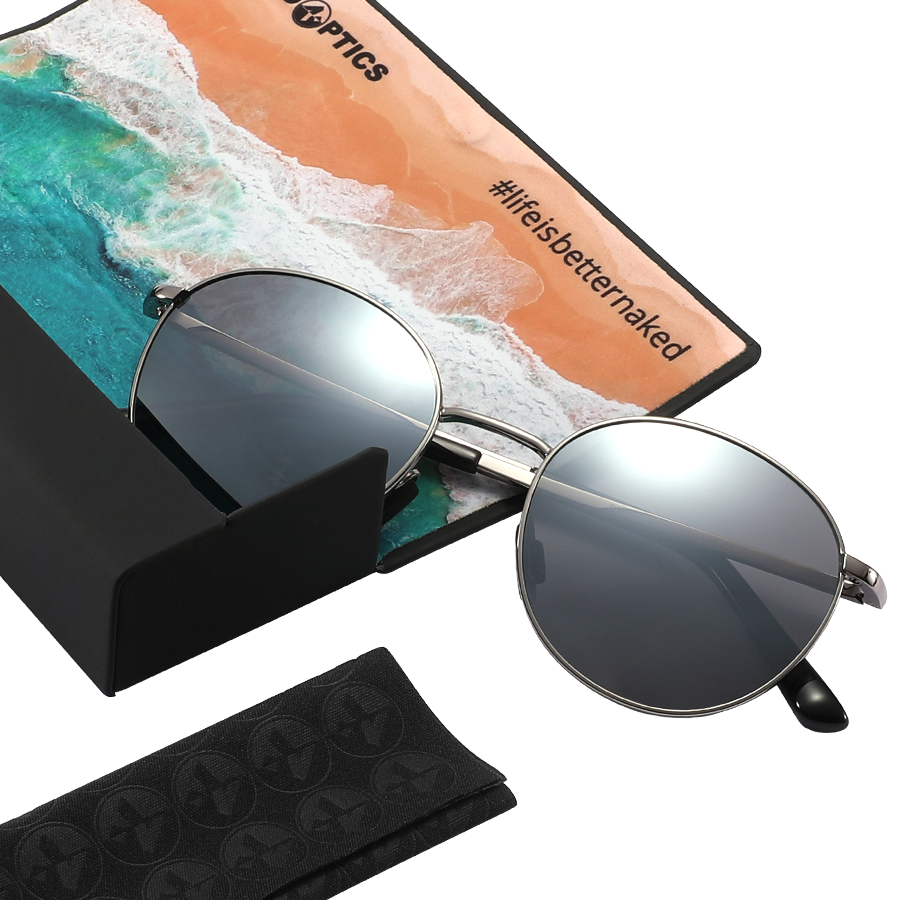 The PARKER round sunglasses by NAKED Optics feature a silver metal frame and provide UV400 protection; they come with a beach-themed cleaning cloth and a sleek black case, all presented on a white background.