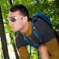 Ein Wanderer, der eine helle RAVE-Sonnenbrille mit Rundum-Rahmen trägt, in einem Wald.
