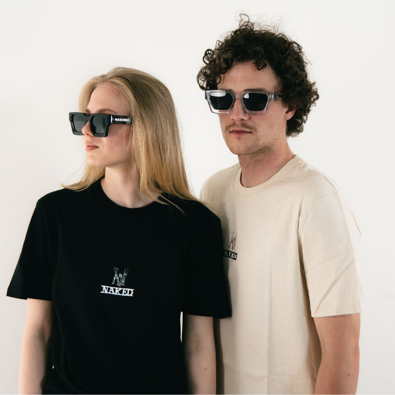 Zwei Personen mit Sonnenbrillen und schlichten T-Shirts stehen nebeneinander vor einem weißen Hintergrund.