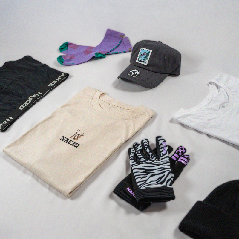 Verschiedene Kleidungsstücke, ausgebreitet auf einem hellen Hintergrund: Socken, Handschuhe, T-Shirts, eine Mütze und eine Strickmütze.