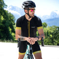A man in black cycling gear and helmet leans on a bike outdoors, wearing The RUSH Halfframe by NAKED Optics—a sport sunglass with UV400 protection—with mountains and trees in the background.