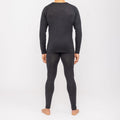 Una persona è in piedi a piedi nudi, di spalle, e indossa un completo coordinato composto da una maglia a maniche lunghe scura e da leggings della linea NAKED Optics Thermo-Unterwäsche Herren (100% lana merino).