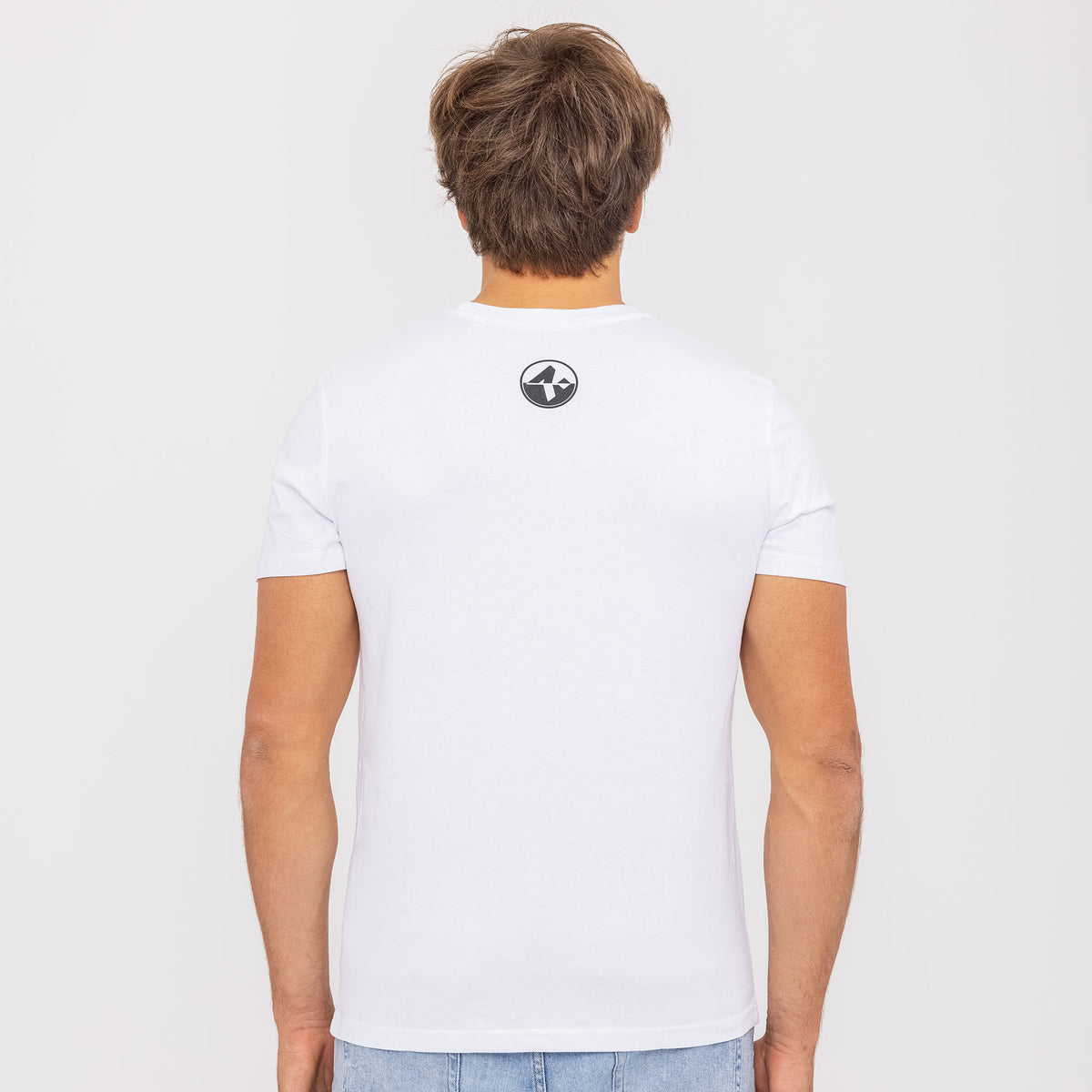 A man with brown hair faces away, wearing the NAKED Optics T-Shirt Skiing-Girl—a plain white shirt featuring a small black logo on the back. Crafted from Fair Wear Bio-Baumwolle, this shirt offers a unique design for eco-friendly style.