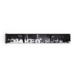Schwarz-weiße Stadt-Skyline mit dem Wort „NAKED“ in fetten weißen Buchstaben über den Gebäuden, die an den eleganten Stil der Werbeanzeigen für die „Extra Strap“-Modelle von NAKED Optics – FORCE EVO, TROOP EVO, STORM, NOVA, SOLAR, ZEND (45 mm) – erinnert.