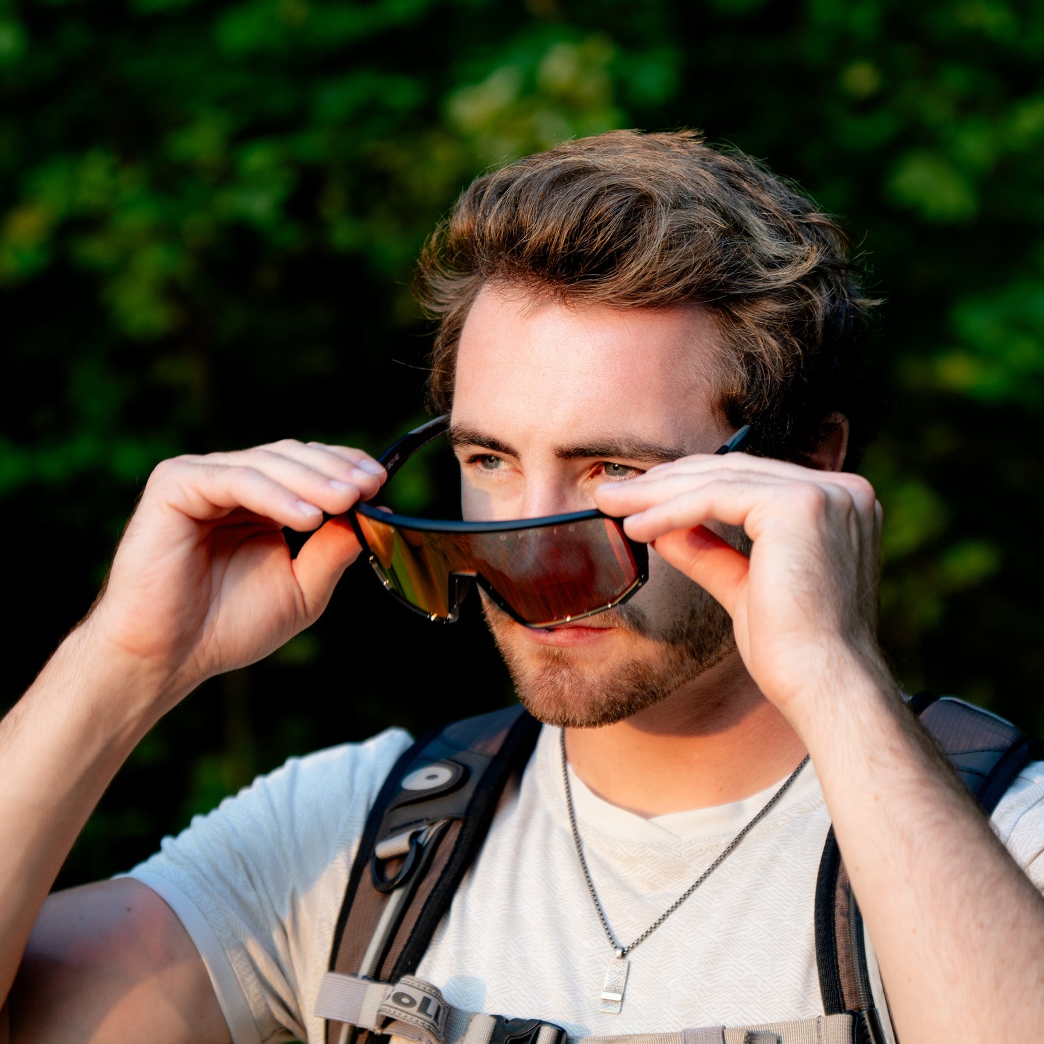 Ein junger Mann steht in der Sonne und setzt gegen das Blenden eine Sportbrille auf; Credits: Elias Neier