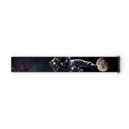 Ein im Weltraum schwebender Astronaut streckt die Hand nach einem fernen Planeten aus, wobei er durch den NAKED Optics Extra Strap (45 mm) für FORCE EVO, TROOP EVO, STORM, NOVA, SOLAR und ZEND sicher an einem schwarzen, rechteckigen Objekt befestigt ist.