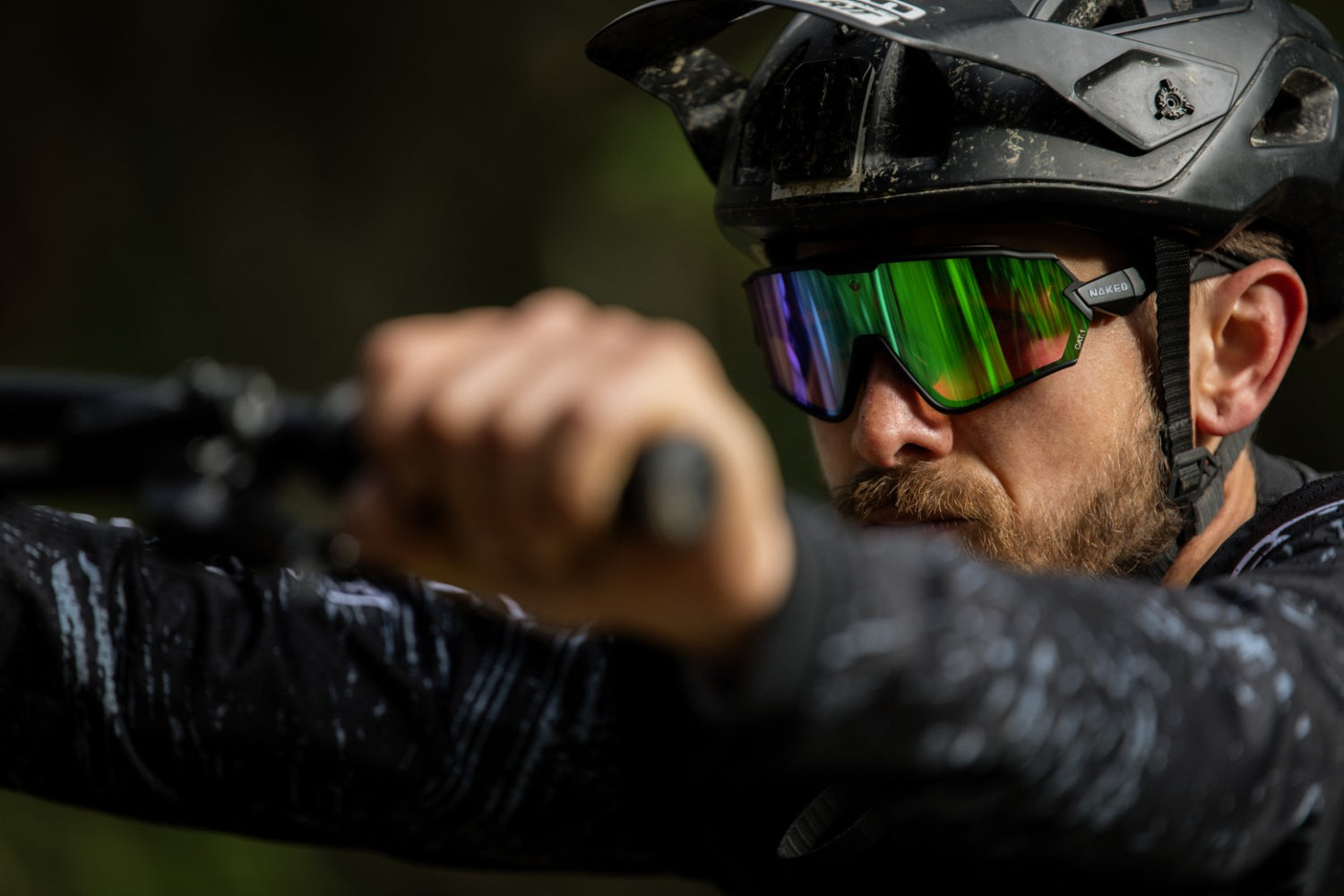 Ein Mann schiebt ein Mountainbike, sein MTB Helm und seine Sportbrille sind im Fokus; Credits: Florian Dorn