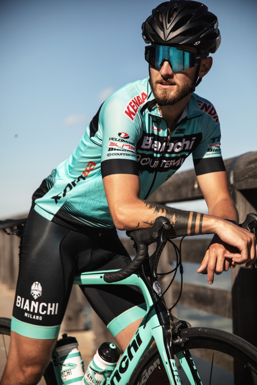 Ein Mann mit einer blauen Fahrradbrille lehnt auf seinem Rennrad; Credits: Flo Dorn