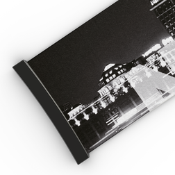 Schwarz-Weiß-Foto von Stadtgebäuden bei Nacht, das teilweise auf einer rechteckigen, schräg stehenden Fläche zu sehen ist – es erinnert an das markante Design des NAKED Optics Extra Strap (45 mm) für die Skibrillen FORCE EVO, TROOP EVO, STORM, NOVA, SOLAR und ZEND.