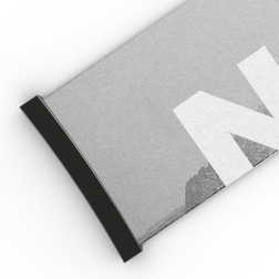 Nahaufnahme einer grauen Matte mit schwarzem Rand und einem großen weißen Buchstaben „N“, der teilweise auf der Oberfläche zu erkennen ist und an das elegante Design des 45-mm-Extra-Armbands für die Modelle FORCE EVO, TROOP EVO, STORM, NOVA, SOLAR und ZEND von NAKED Optics erinnert.