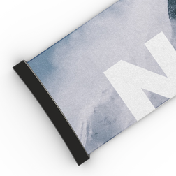 Eine Nahaufnahme eines aufgerollten NAKED Optics Extra Strap (45 mm) mit schwarzem Rand und großem weißem Schriftzug auf blaugrauem Hintergrund, inspiriert vom markanten Design der Modelle FORCE EVO, TROOP EVO, STORM, NOVA, SOLAR und ZEND.