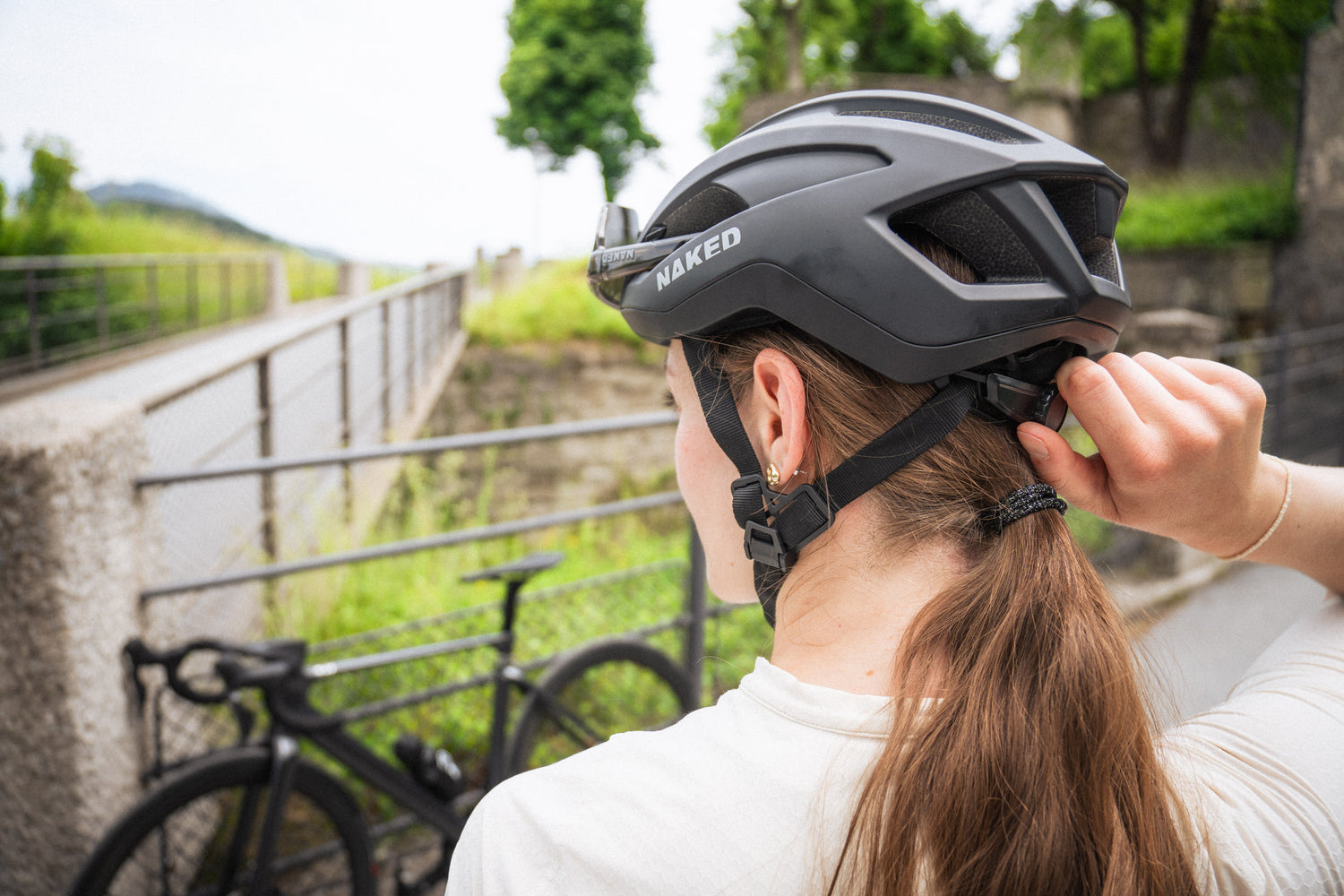 Eine Radfahrerin steht mit dem Rücken zur Kamera, so wird der Verstellmechanismus des Fharradhelmes sichtbar; Credits: Elias Neier