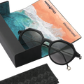 The IZZY by NAKED Optics is a black, round sunglasses model with an acetate frame and UV400 protection, and it comes with a cleaning cloth featuring a beach scene and the text “lifeisbetterwalked.”.