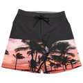 The SHORE Boardshorts by NAKED Optics are crafted from 4-way stretch material and showcase a vibrant tropical palm tree sunset print with a NAKED label on the left leg—perfect for surfing and beach adventures.
