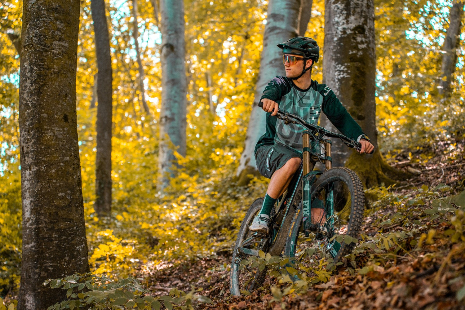 Ein Mountainbiker fährt auf seinem Bike durch den Wald und hat einen MTB Helm auf; Credits: Kathy Lerchner