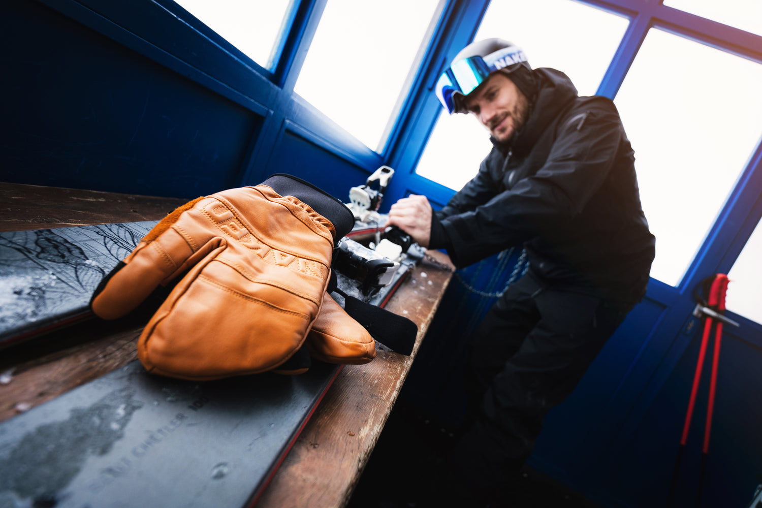Ein Mann stellt seine Skibindung ein, vor ihm liegt ein Leder-Handschuh; Creits: Elias Neier