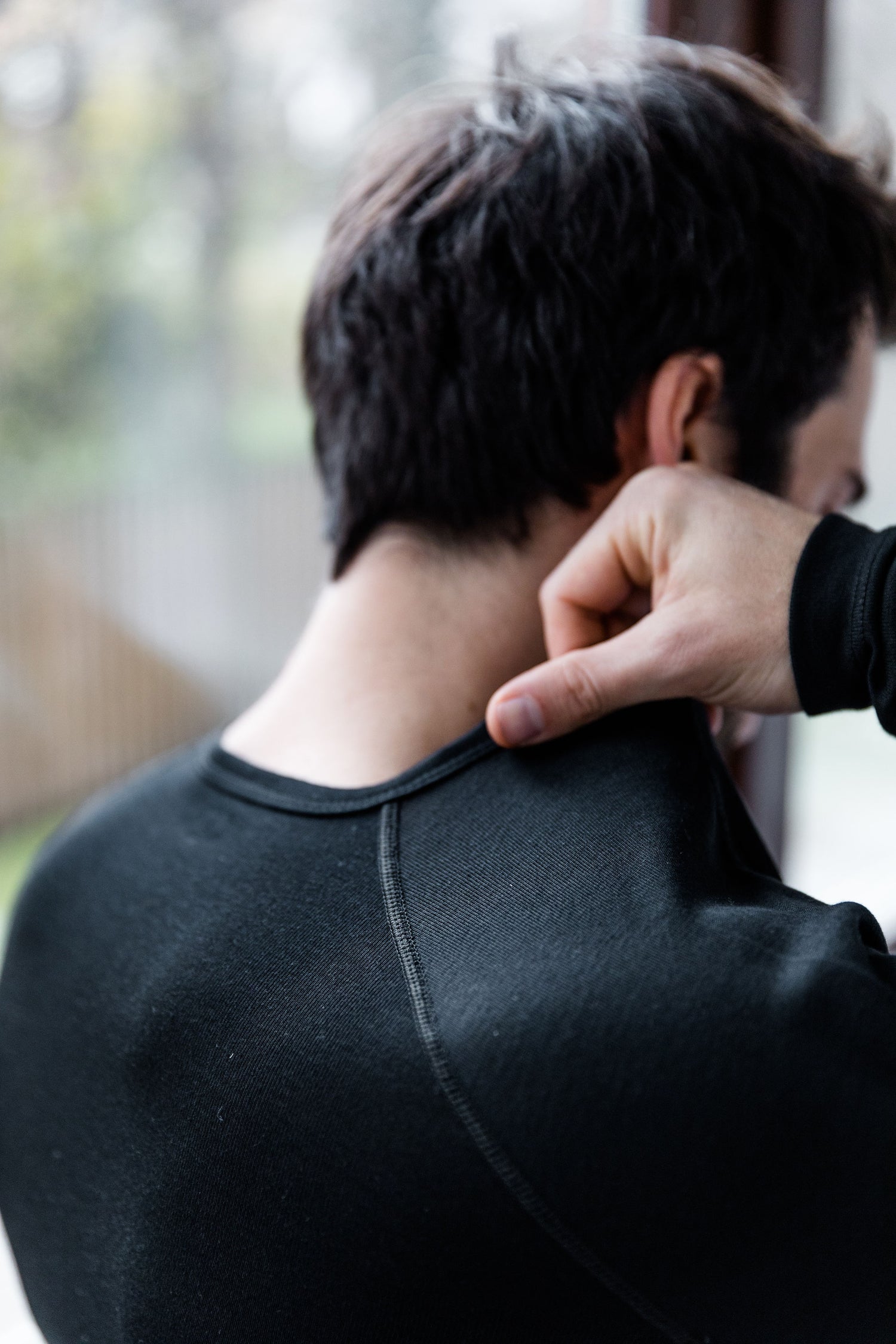Ein Mann steht am Fenster und zieht sich gerade seine Merino-Skiunterwäsche an; Credits: Michi Dullnig
