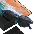 The LUNA sunglasses by NAKED Optics in blue with polarized lenses, displayed alongside a black case, cleaning cloth, and a beach-themed card that reads #lifeisbetternaked.