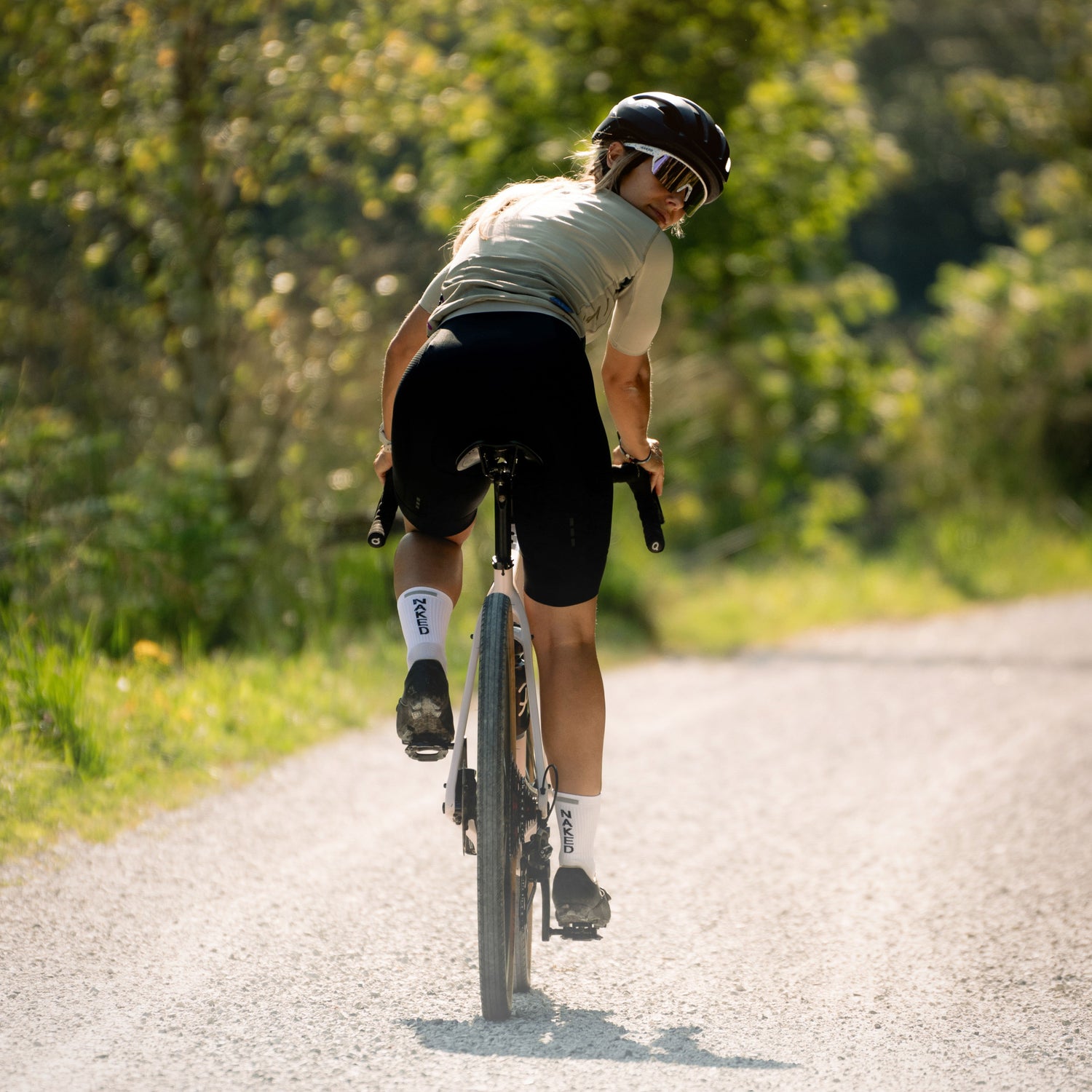 Eine junge Frau fährt mit dem Fahrrad und dreht ihren Kopf über die Schulter, gut sind ihre Fahrradsocken zu sehen; Credits: Elias Neier