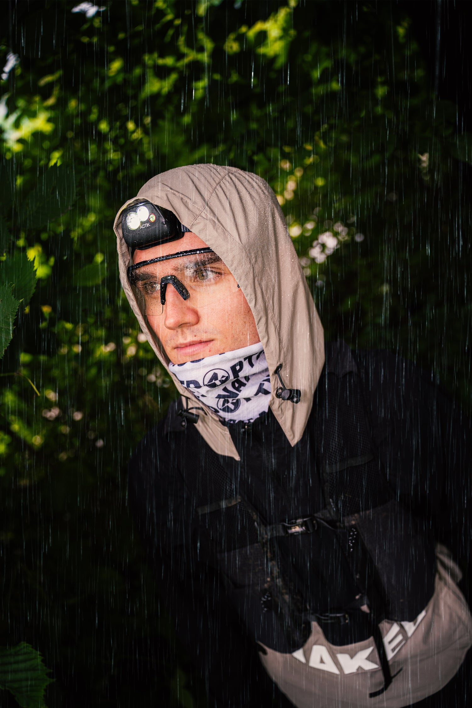 Ein Mann steht im Regen, eine Kapuze über den Kopf gezogen ein Bandana über das Kinn; Credits: Elias Neier