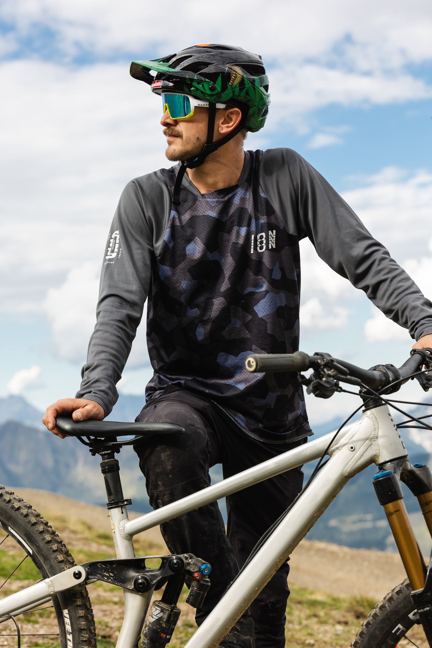 Ein Mountainbiker steht hinter seinem Fahrrad und schaut in dei Sonne, seine weiße Fahrradbrille schützt seine Augen; Credits: Flo Dorn