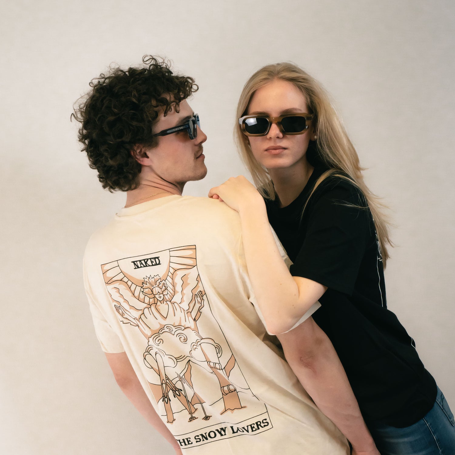 Ein Paar tärgt modische Sonnenbrillen und T-Shirts, der Mann dreht sich mit dem Rücken zur Kamera und zeigt den Back-Print seines Shirts; Credits: Elias Neier