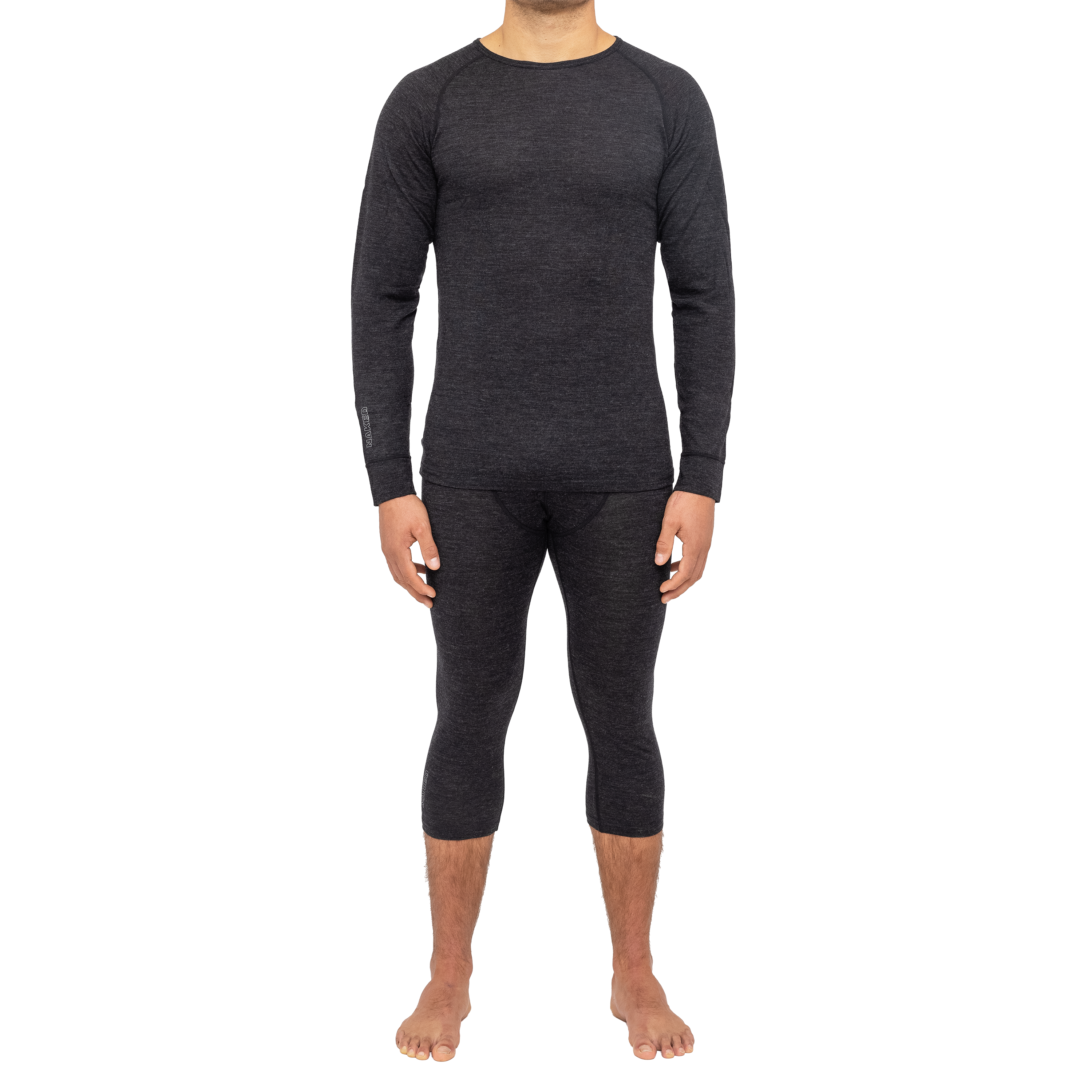 Eine Person, die passende dunkle NAKED Optics Merino Unterwäsche trägt - ein langärmeliges Oberteil und verkürzte Leggings - und barfuß ist.