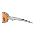 Maak kennis met de HAWK van NAKED Optics: een strakke, zilverkleurige sportzonnebril met een hoekig montuur, oranje spiegelglazen en het kenmerkende NAKED-logo op de poot – hier te zien in zijaanzicht. Deze stijlvolle fietsbril voor kleine hoofden is vakkundig ontworpen voor een perfecte pasvorm en optimale prestaties.