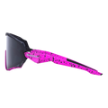 Vista laterale degli occhiali sportivi NAKED Optics: gli occhiali da ciclismo HAWK per bambini, caratterizzati da un design a spruzzi di colore rosa brillante e lenti scure su sfondo bianco.
