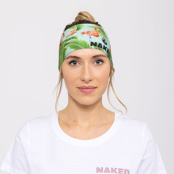 Eine Frau steht vor einem schlichten Hintergrund und trägt ein weißes NAKED Optics Shirt und ein buntes tropisches Sportstirnband von NAKED Optics.